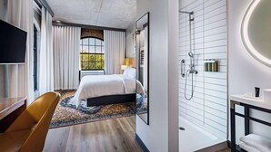 A modern hotel room with a large bed, a shower area, a desk, and a television. - The Loom Hotel, Tapestry Collection by Hilton (Warwick)