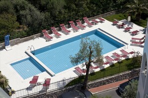 A rectangular swimming pool with two smaller pools on either side, surrounded by lounge chairs and umbrellas.