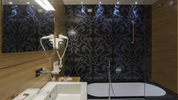 Um banheiro moderno com um espelho grande, uma pia branca, uma banheira preta e um chuveiro com porta de vidro.