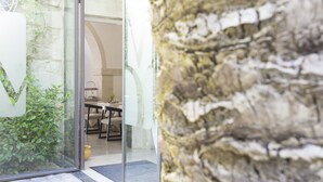 Un interior moderno con una pared de piedra, una puerta de cristal que da a un comedor y una planta en maceta.