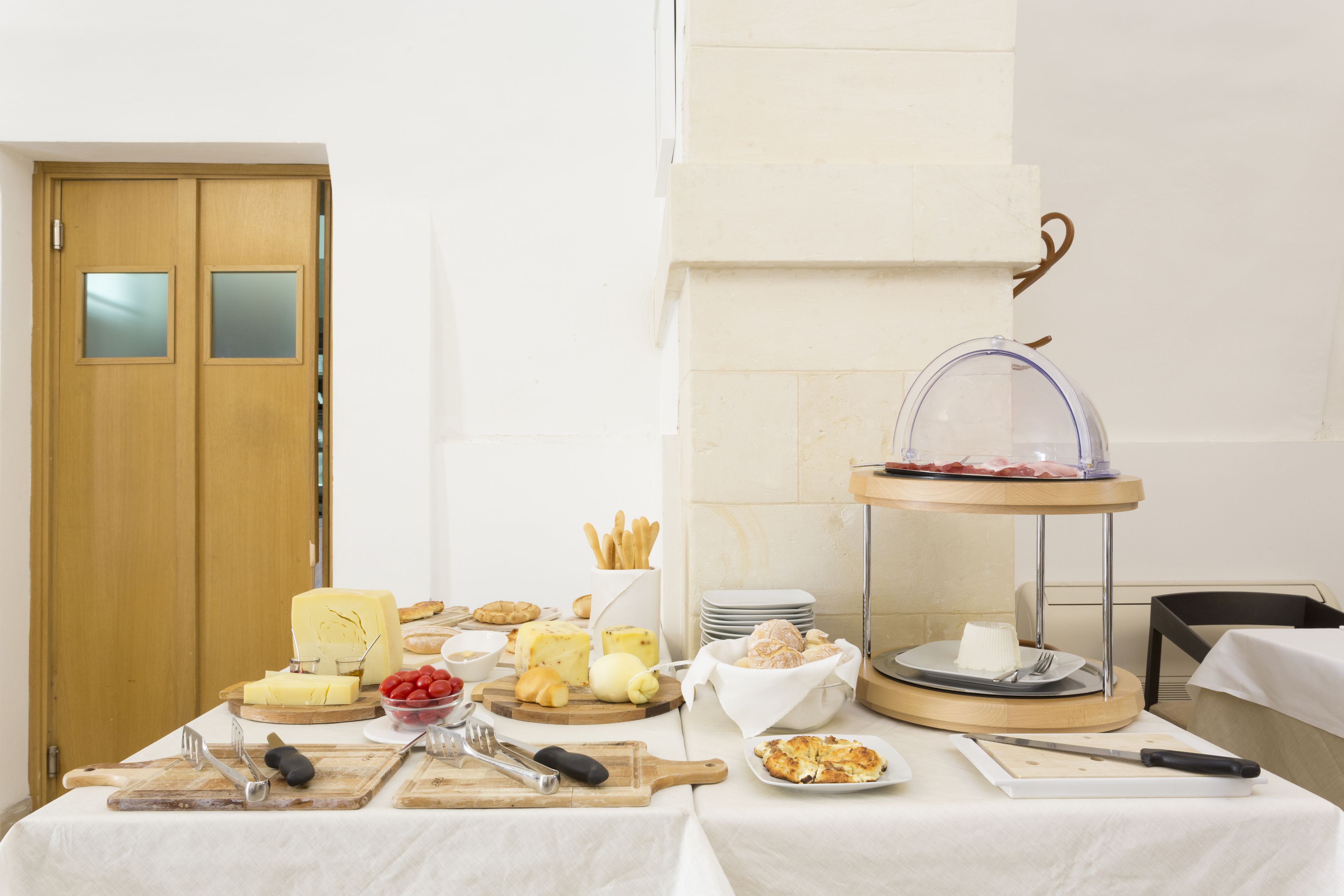 A breakfast buffet with various cheeses, fruits, and pastries on a table.