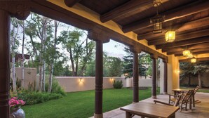 Une terrasse extérieure avec des tables et des chaises en bois, une pelouse bien entretenue et une vue sur les arbres environnants.