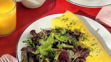 A breakfast setting with a croissant, coffee, orange juice, and a plate of omelette with salad.
