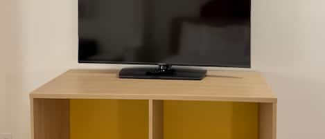 Un televisor de pantalla plana montado en la pared sobre un mueble de televisión de madera con dos estantes.