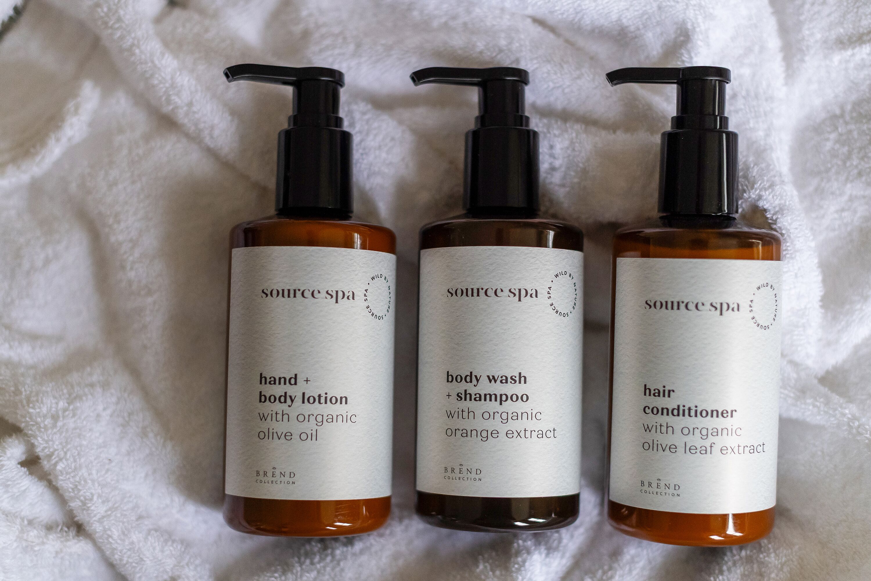 Trois bouteilles de produits de la gamme Source Spa, posées sur une serviette blanche.