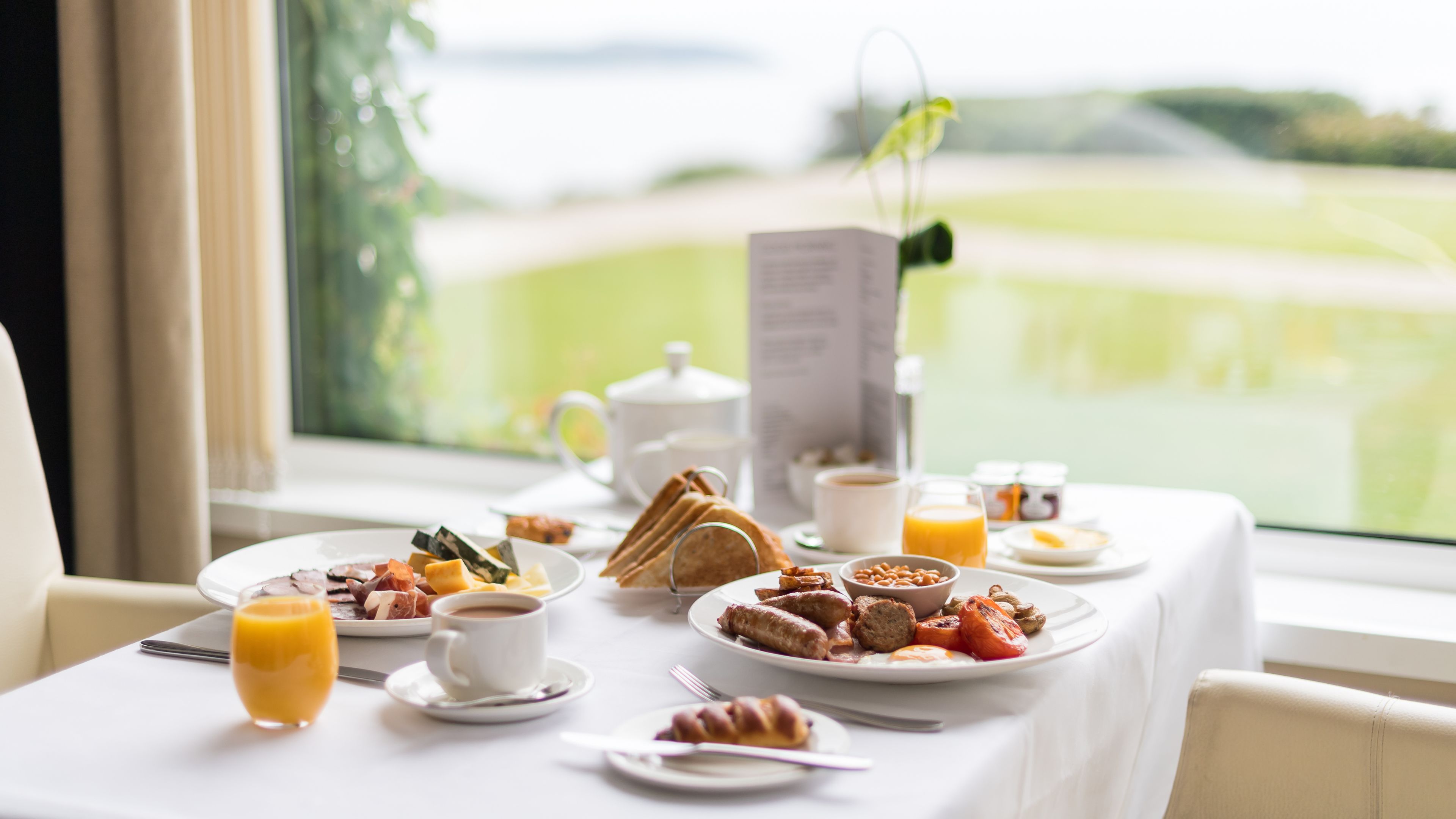 A breakfast table with plates of food, a coffee cup, and a glass of orange juice.