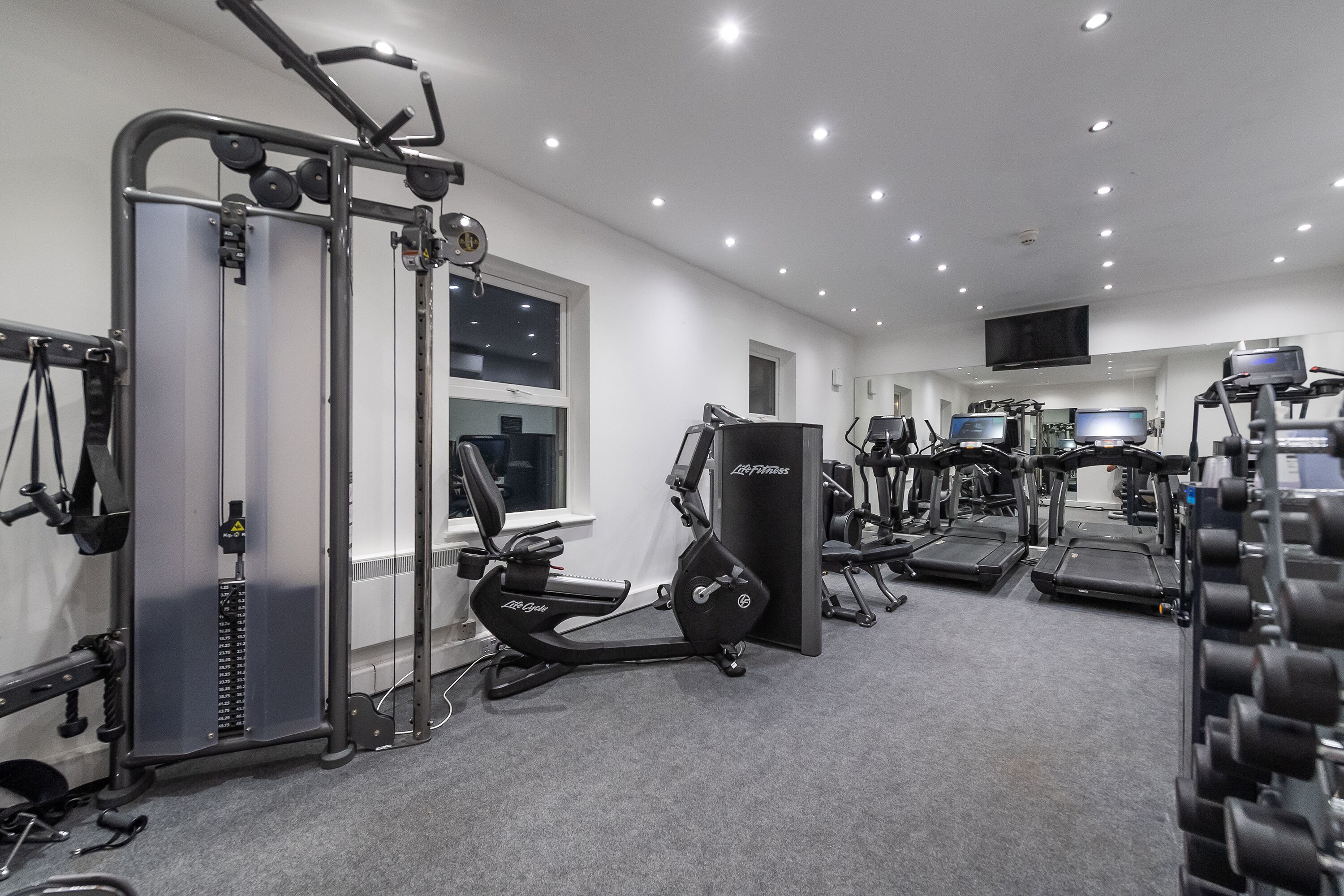 A gym with cardio machines, weight benches, and free weights.
