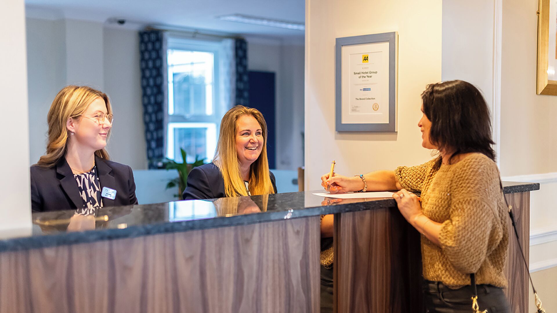 A reception area with a counter, framed awards on the wall, and a window in the background.