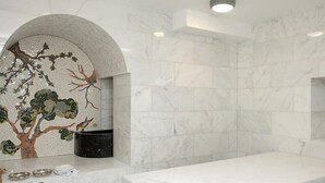 A bathroom with a marble sink, a tree mural, and a stone wall. - The Bell Boutique Hotel (Tel Aviv)