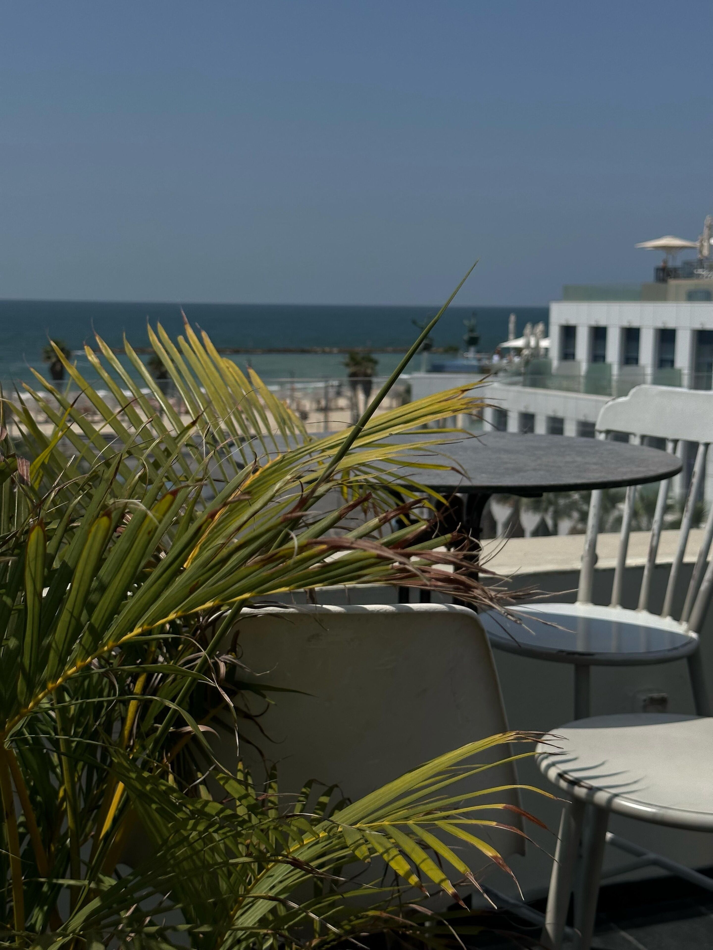 A terrace with a table and chairs, overlooking a body of water and a building in the background.