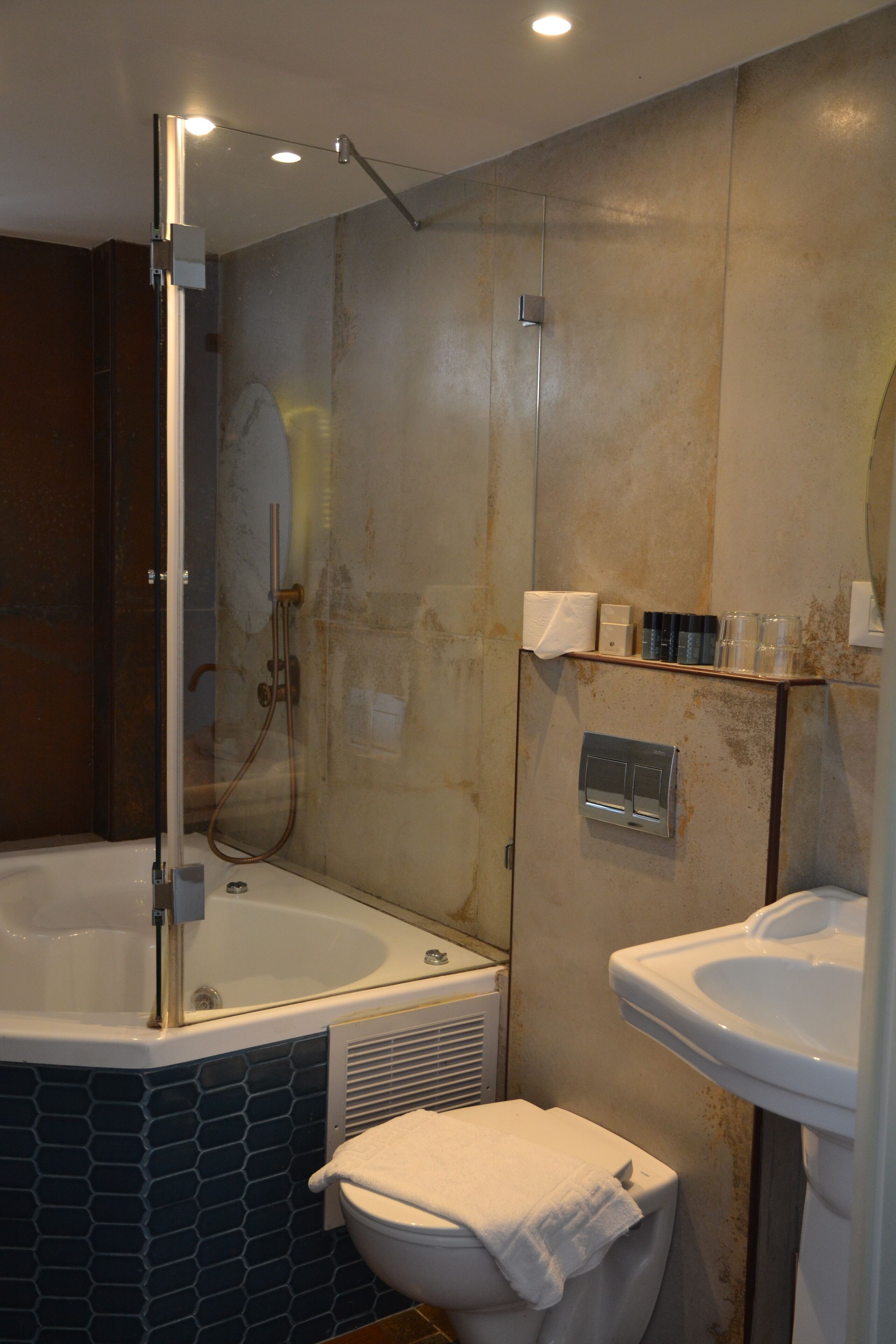 Un baño con ducha envuelta en vidrio, una bañera independiente y un lavamanos pedestal.