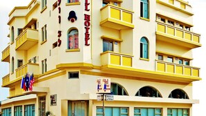 A multi-story hotel with balconies, a sign indicating it is a Bell Hotel, and flags outside. - The Bell Boutique Hotel (Tel Aviv)