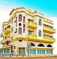 Un hotel de varios pisos con balcones, un cartel que indica que es un Bell Hotel y banderas afuera.