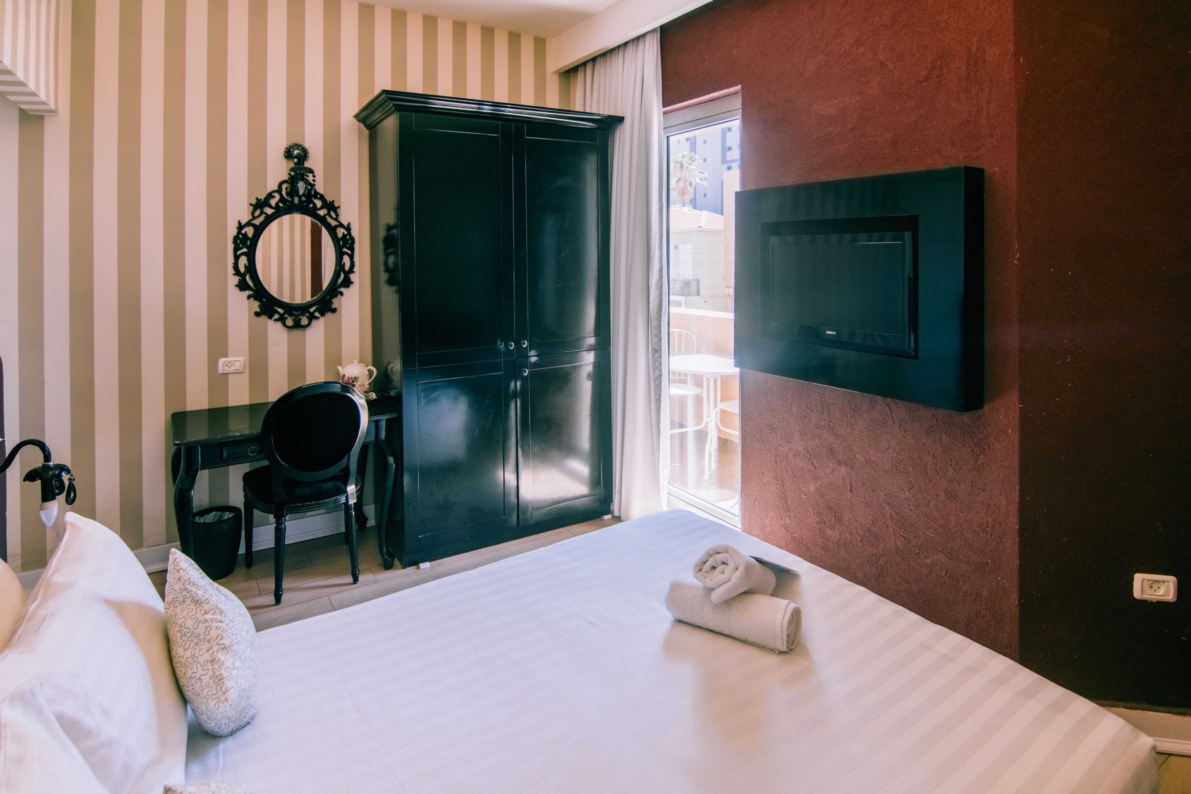 Ein Hotelzimmer mit einem Bett, einem Schreibtisch, einem Stuhl, einem Kleiderschrank und einem Fernseher.