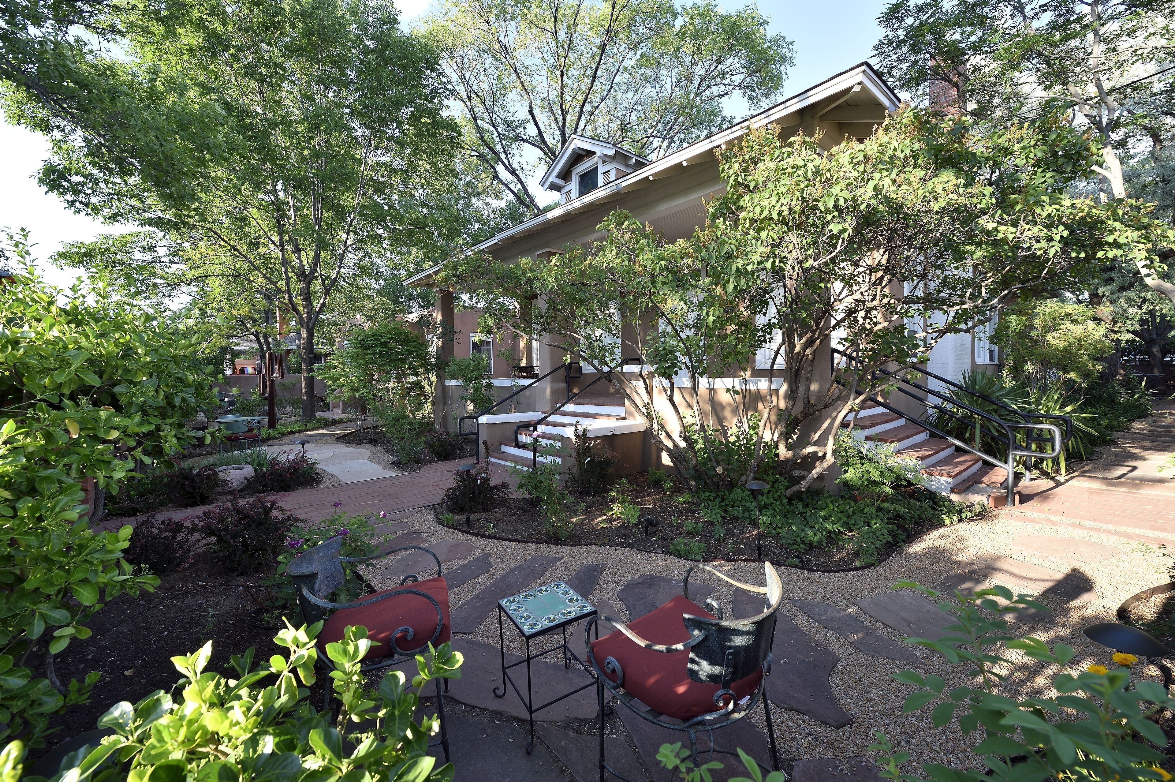A courtyard with a covered seating area, a staircase, and a building with a sloped roof.