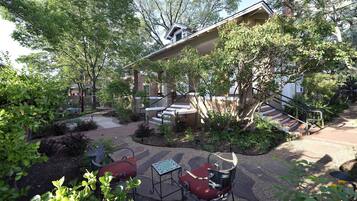 A courtyard with a covered seating area, a staircase, and a building with a sloped roof.