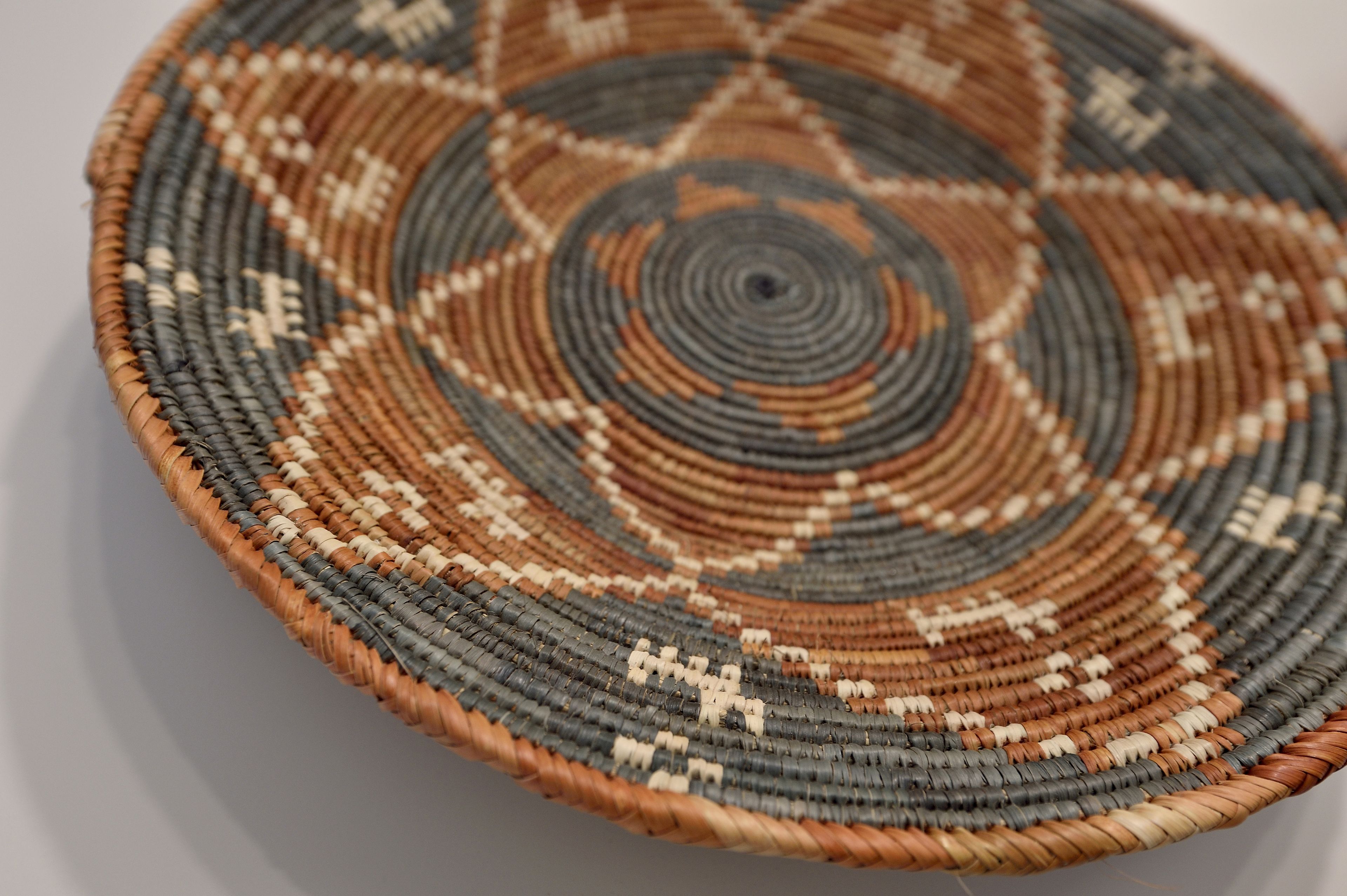A circular woven basket with a geometric pattern.