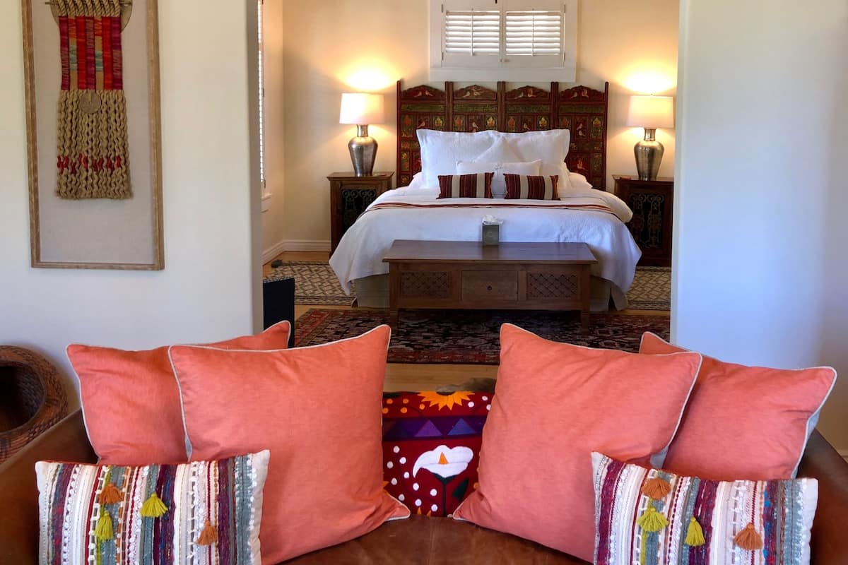 A bedroom with a bed, two bedside tables, a ceiling fan, and a window with shutters.