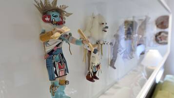 A display of various decorative items, including a figure with a crown and a dog-like figure, mounted on a wall.
