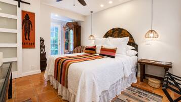 A bedroom with a bed, a ceiling fan, a nightstand, a lamp, and a view of the outside.