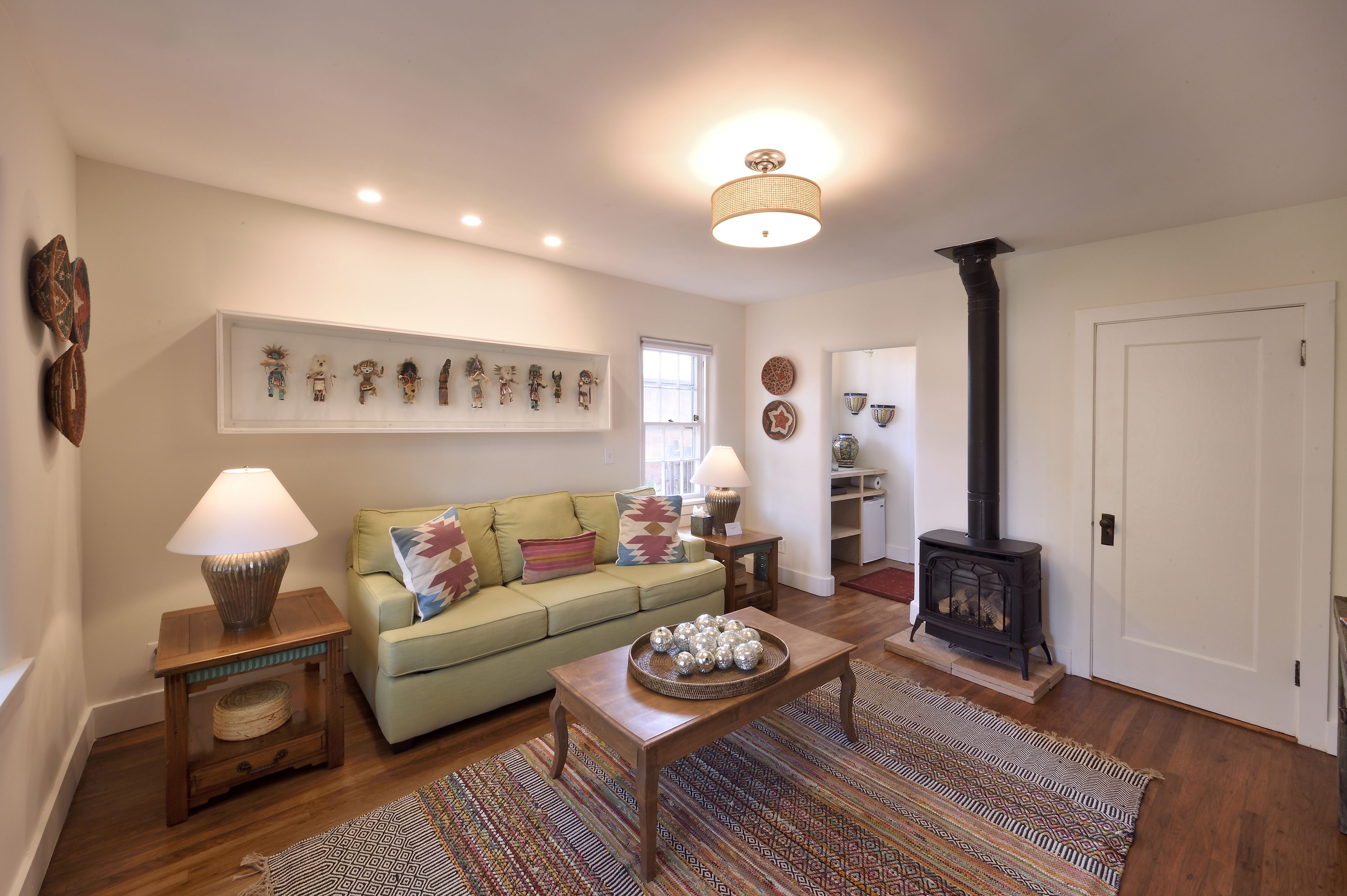 Una sala de estar acogedora con un sofá, una mesa de centro, una chimenea y obras de arte en la pared.