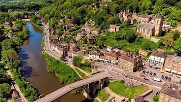 A riverside town with a historic bridge, traditional architecture, and lush greenery.