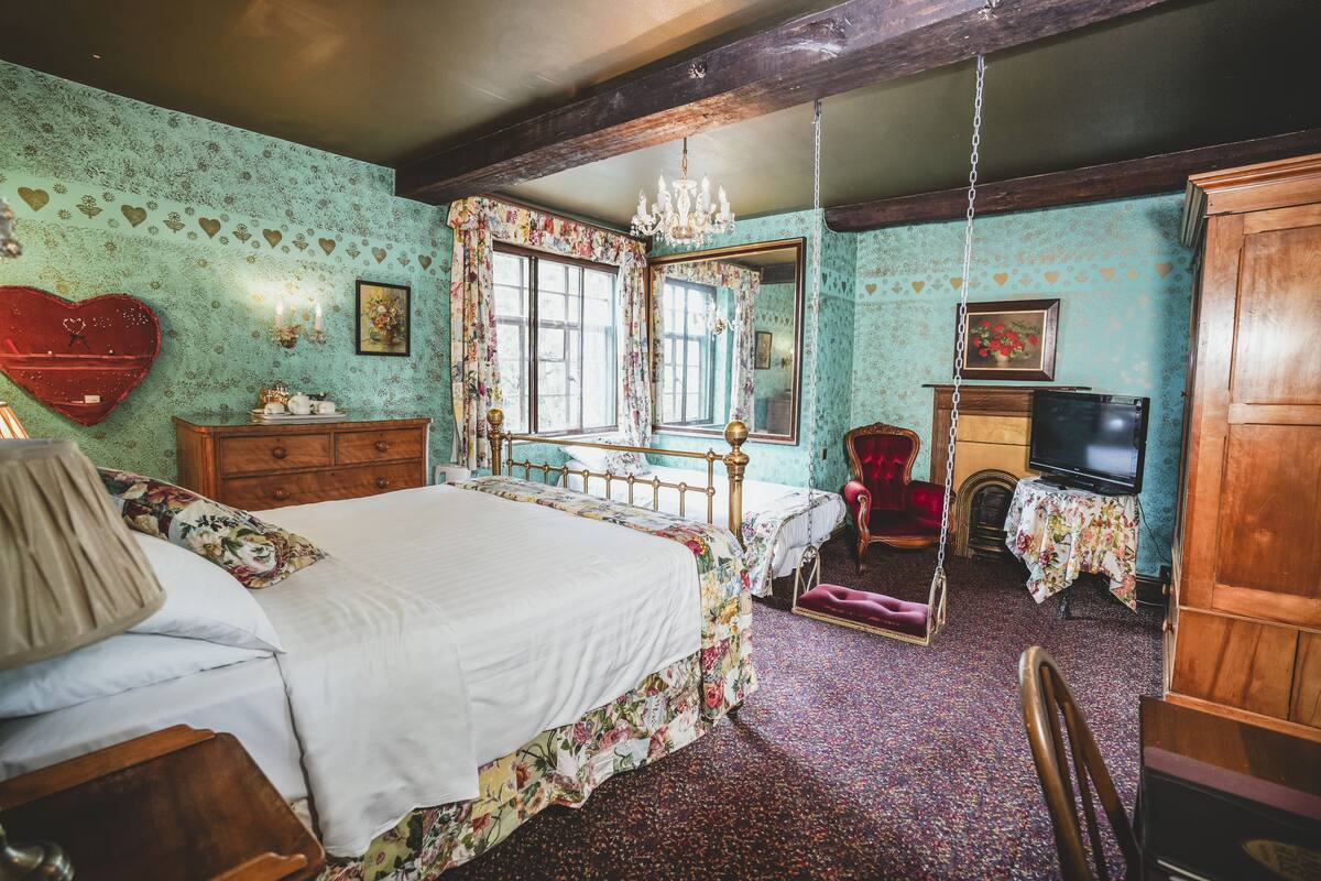 A bedroom with a bed, wooden furniture, a chandelier, and a television.