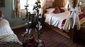 Un dormitorio con una cama de madera, dosel y un arreglo floral.