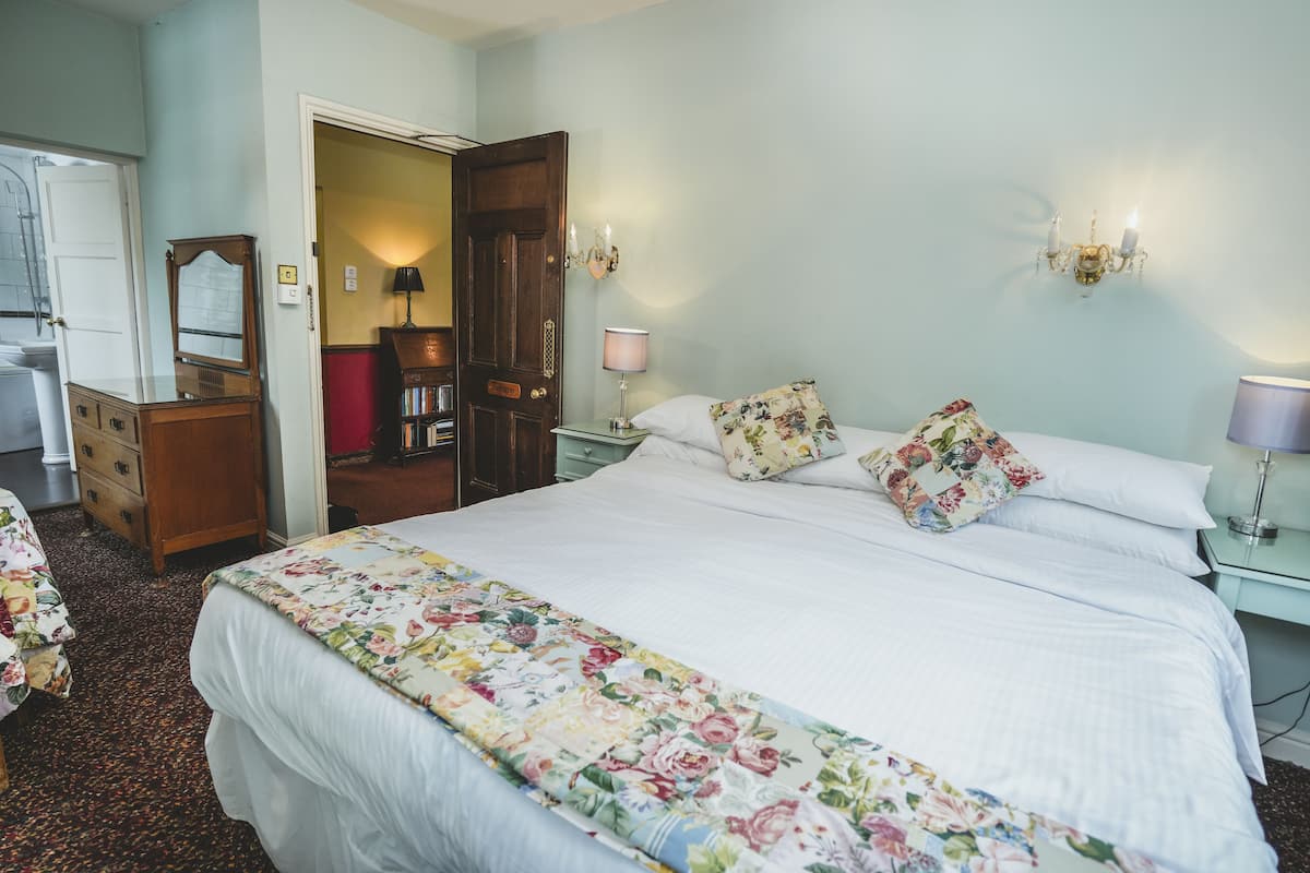 A neatly arranged bedroom with a large bed, bedside tables, a dresser, and a wardrobe.
