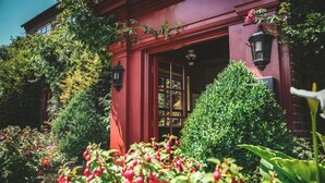 A red building with a garden entrance, a window with a grid pattern, and a small white flower in the foreground. - Hundred House Hotel (Shifnal)