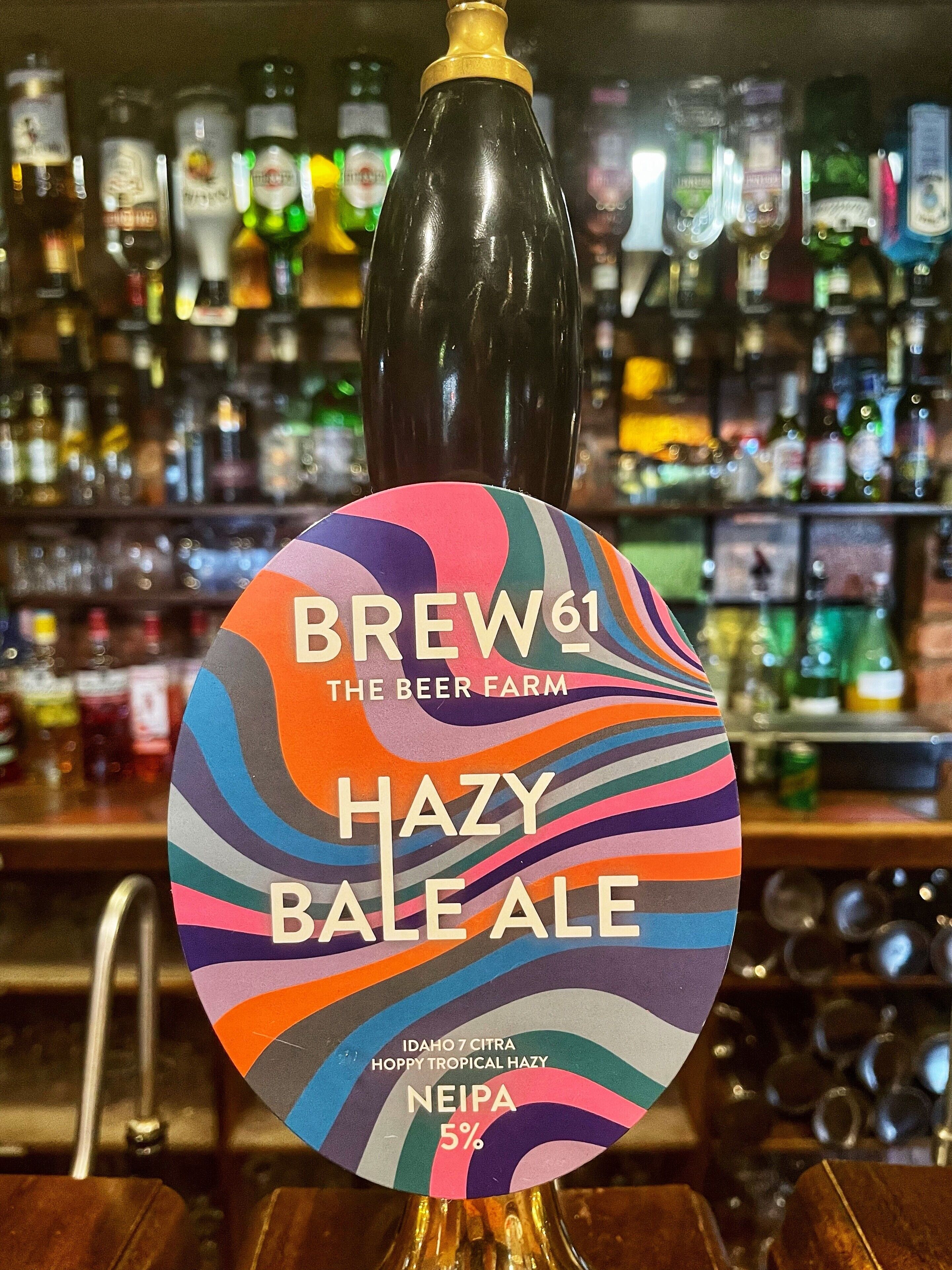 A beer tap labeled "BREW61 HAZY BALE ALE" with a colorful label and a gold top.