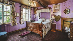 A bedroom with a wooden four-poster bed, a hanging chair, and a fireplace. - Hundred House Hotel (Shifnal)