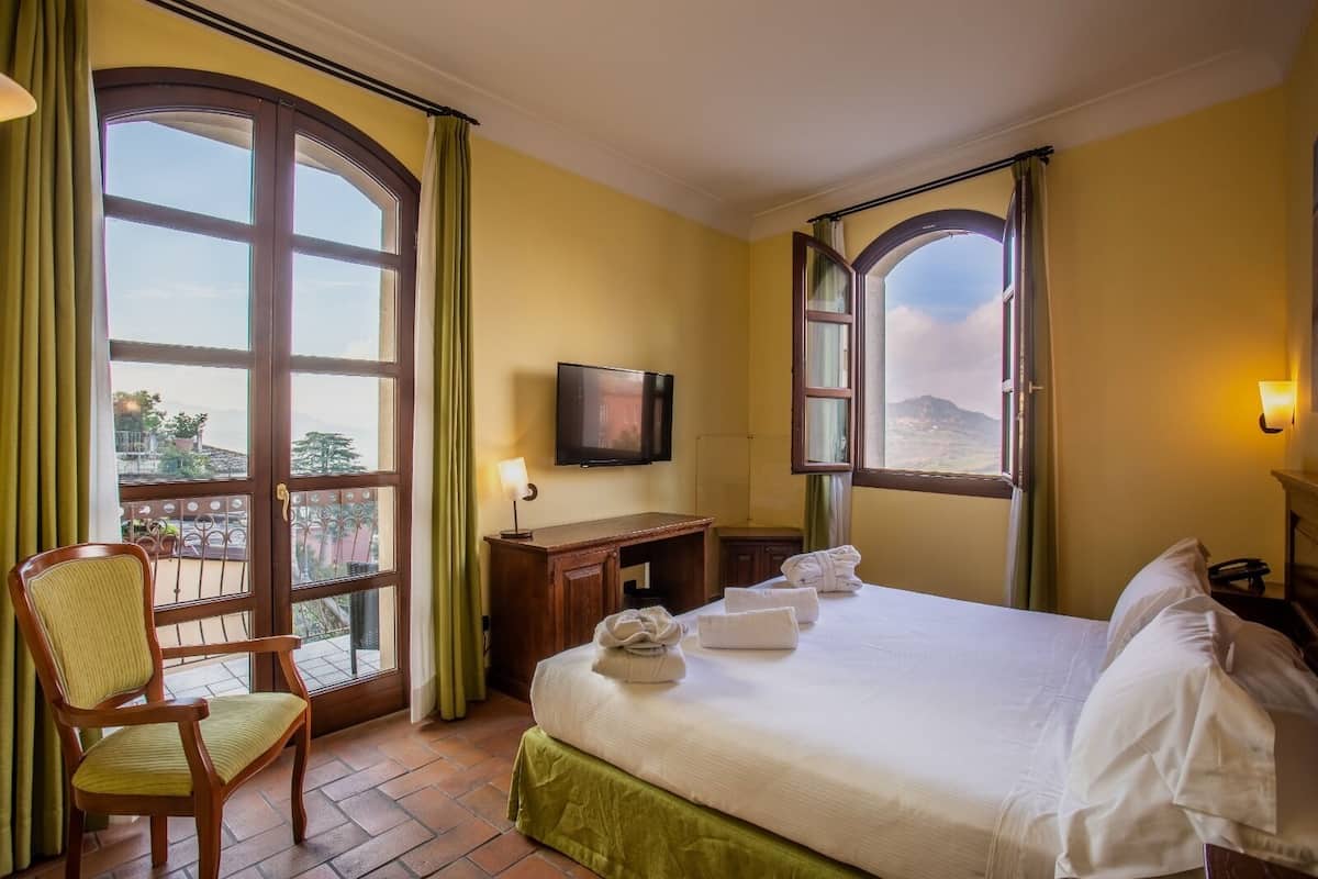 A hotel room with a bed, a desk, a chair, and a TV.
