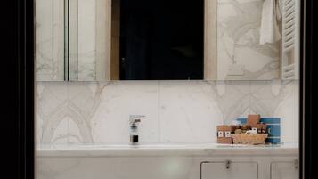 A bathroom with a marble sink, a mirror, a towel rack, and a small stool.