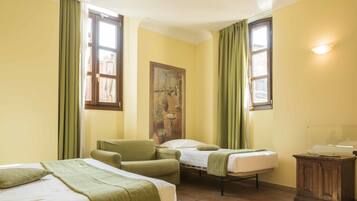 A room with two beds, a chair, a cabinet, and a painting on the wall.