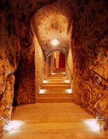 Una escalera de piedra que sube a un nivel superior, con una cortina roja en la parte superior.