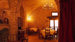 A restaurant with brick arches, wooden tables, and a chandelier. - Oste del Castello Wellness & Bike Hotel (Verucchio)