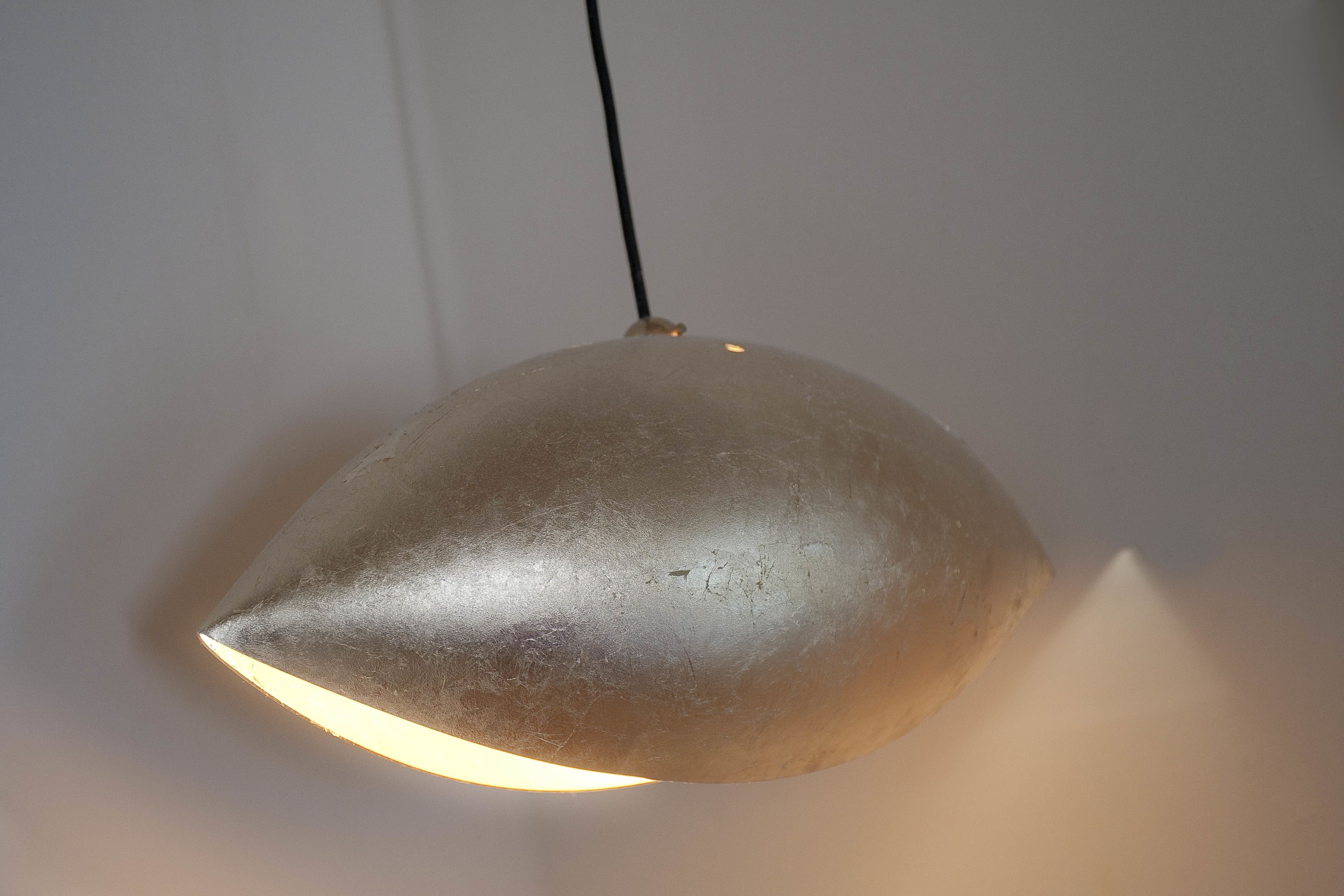 A metallic, dome-shaped pendant light fixture with a single bulb, hanging from a black cord.