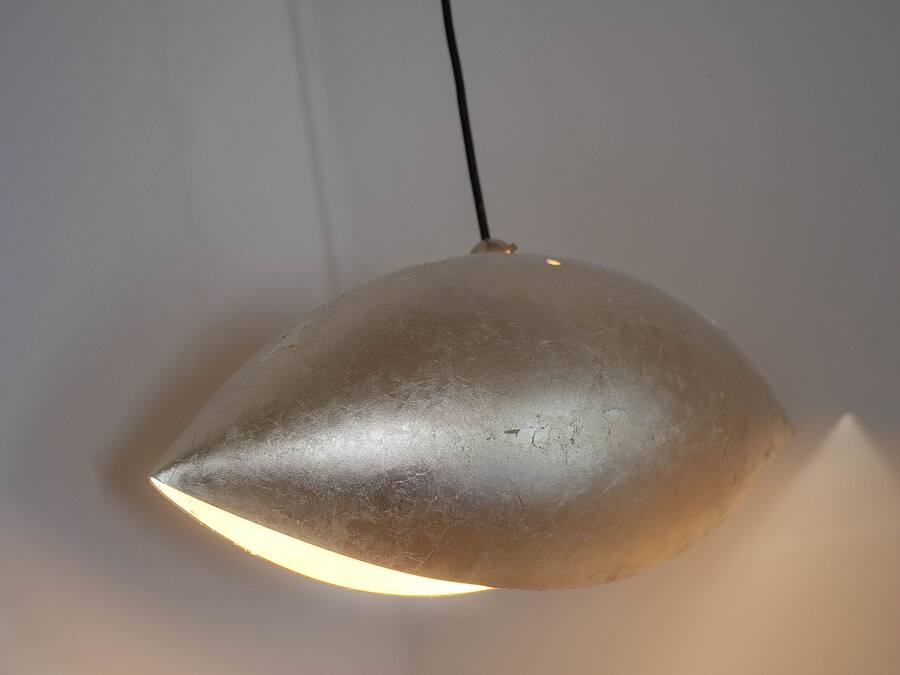 A metallic, dome-shaped pendant light fixture with a single bulb, hanging from a black cord.