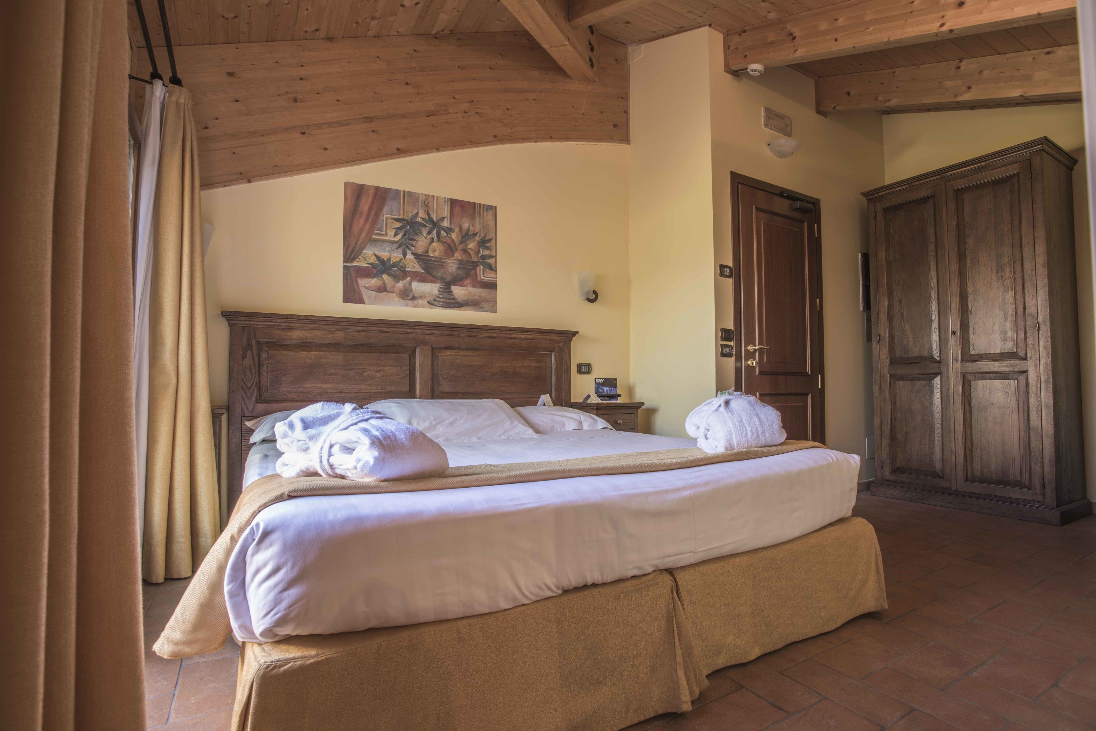 A neatly made bed with a wooden headboard, a nightstand with a lamp, and a large wardrobe.