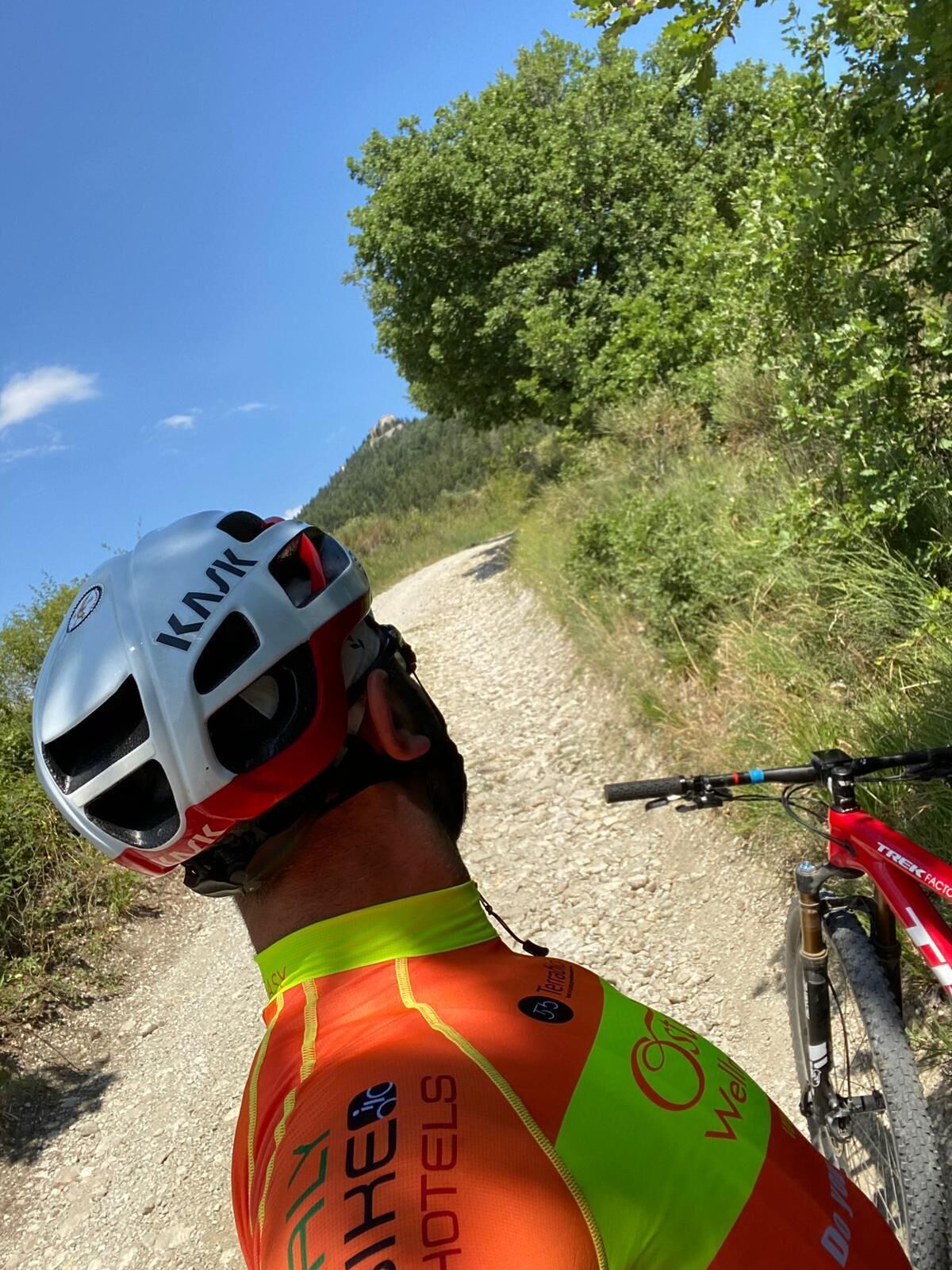 A person wearing a helmet and a reflective vest on a gravel path.