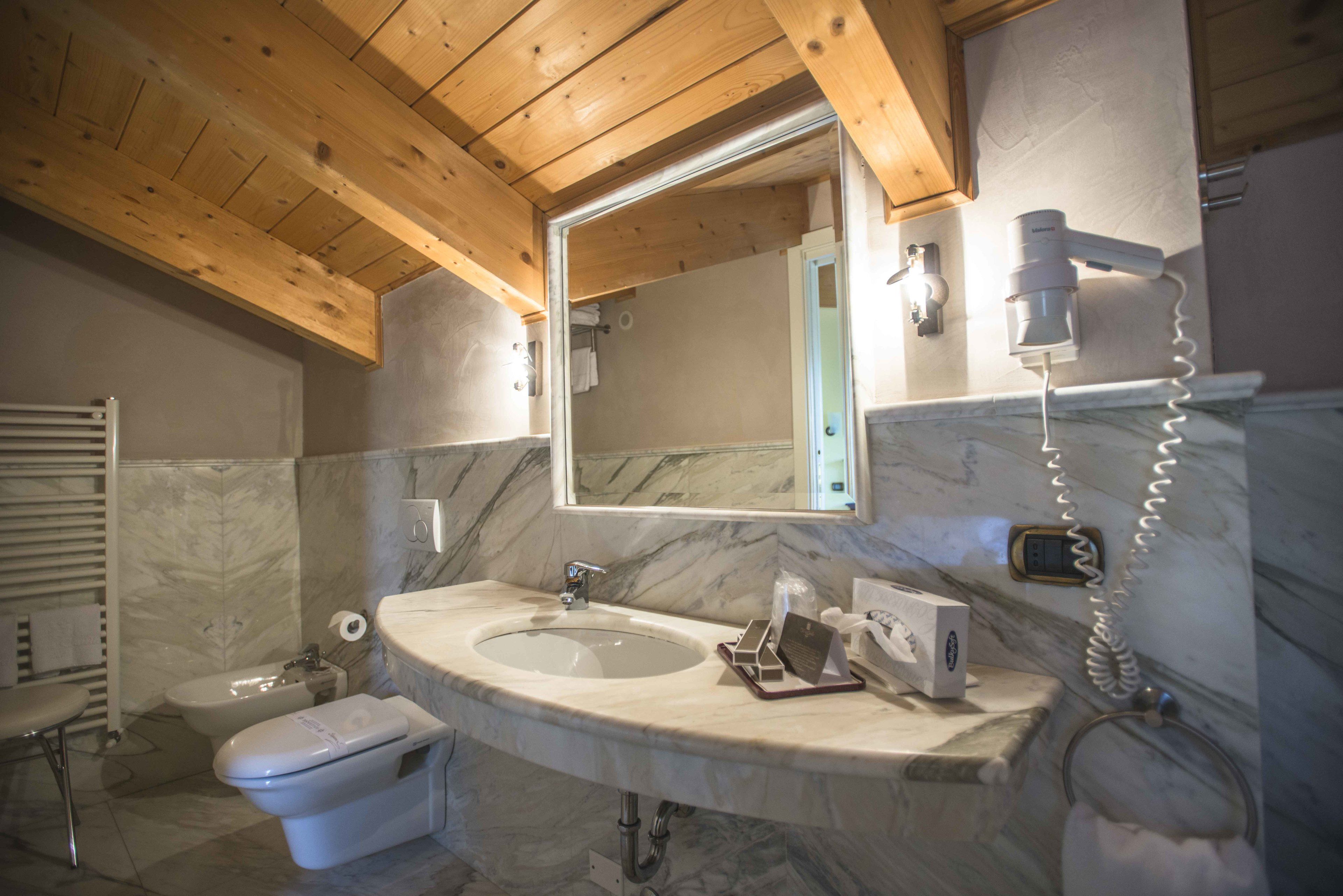 Un baño con techo de madera, lavamanos de mármol y un espejo grande.