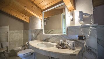Un baño con techo de madera, lavamanos de mármol y un espejo grande.