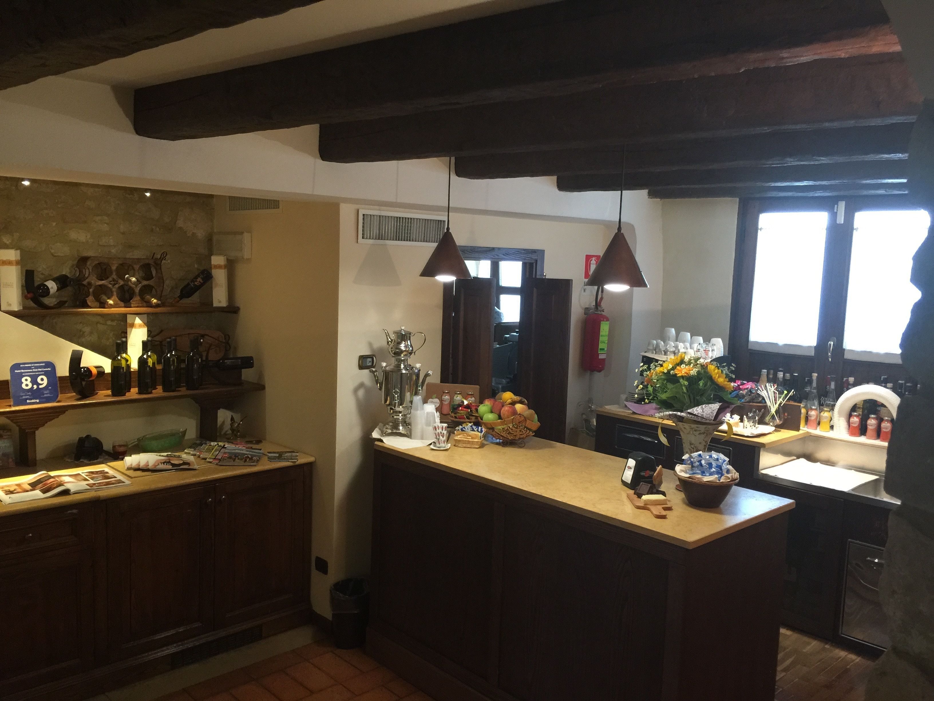 A kitchen with wooden cabinets, a central island with a sink, and a variety of items on the counter including bottles, a fruit basket, and a decorative vase.