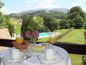 Una mesa dispuesta para el desayuno con vistas a una piscina y colinas.