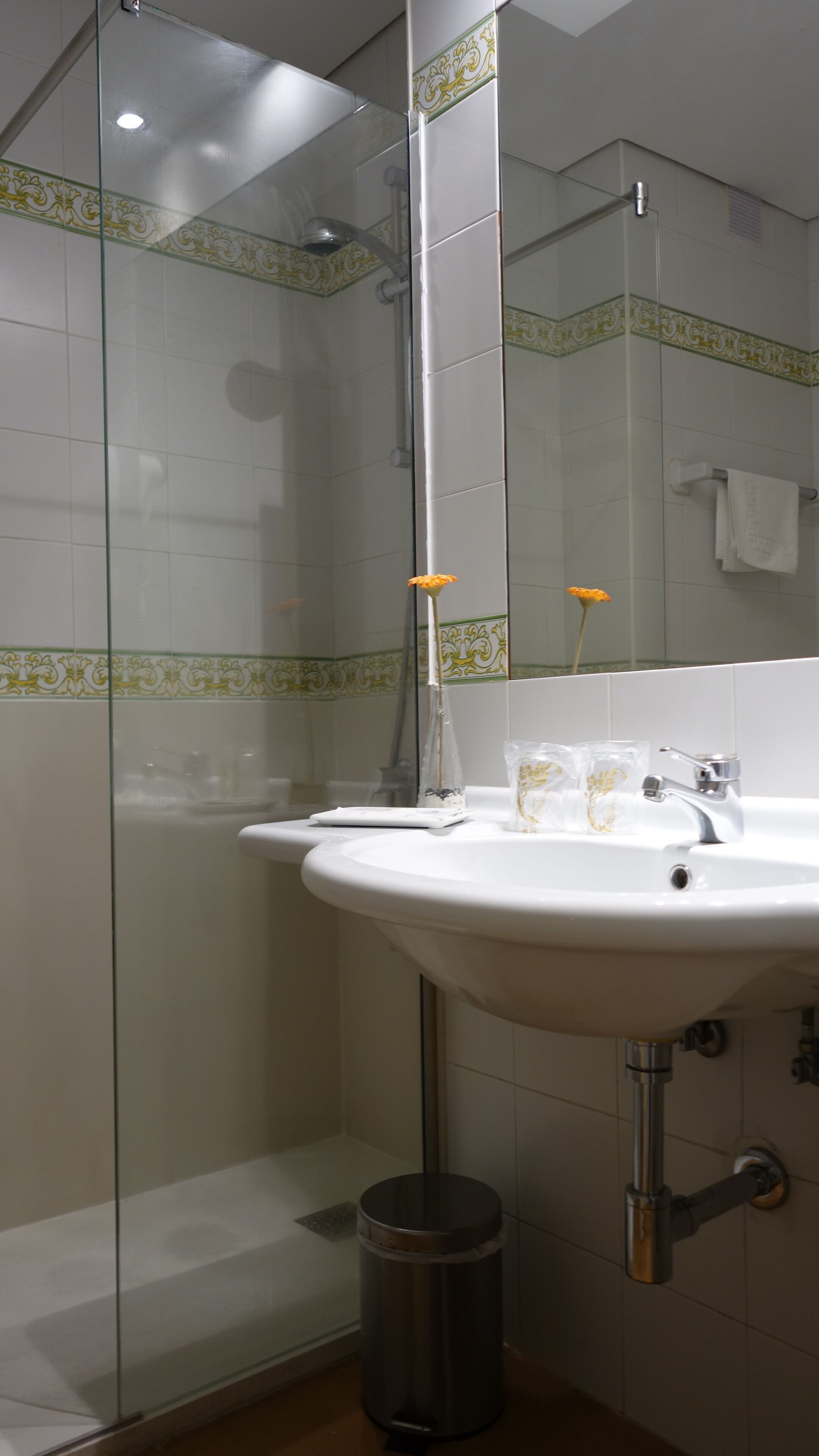 Un baño con cabina de ducha de vidrio, un lavabo blanco y un espejo.