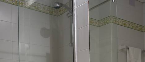 Un baño con cabina de ducha de vidrio, un lavabo blanco y un espejo.