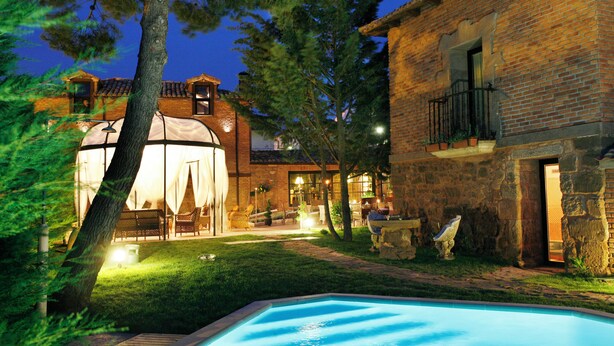 A brick building with a pool, outdoor seating, and a tent-like structure.