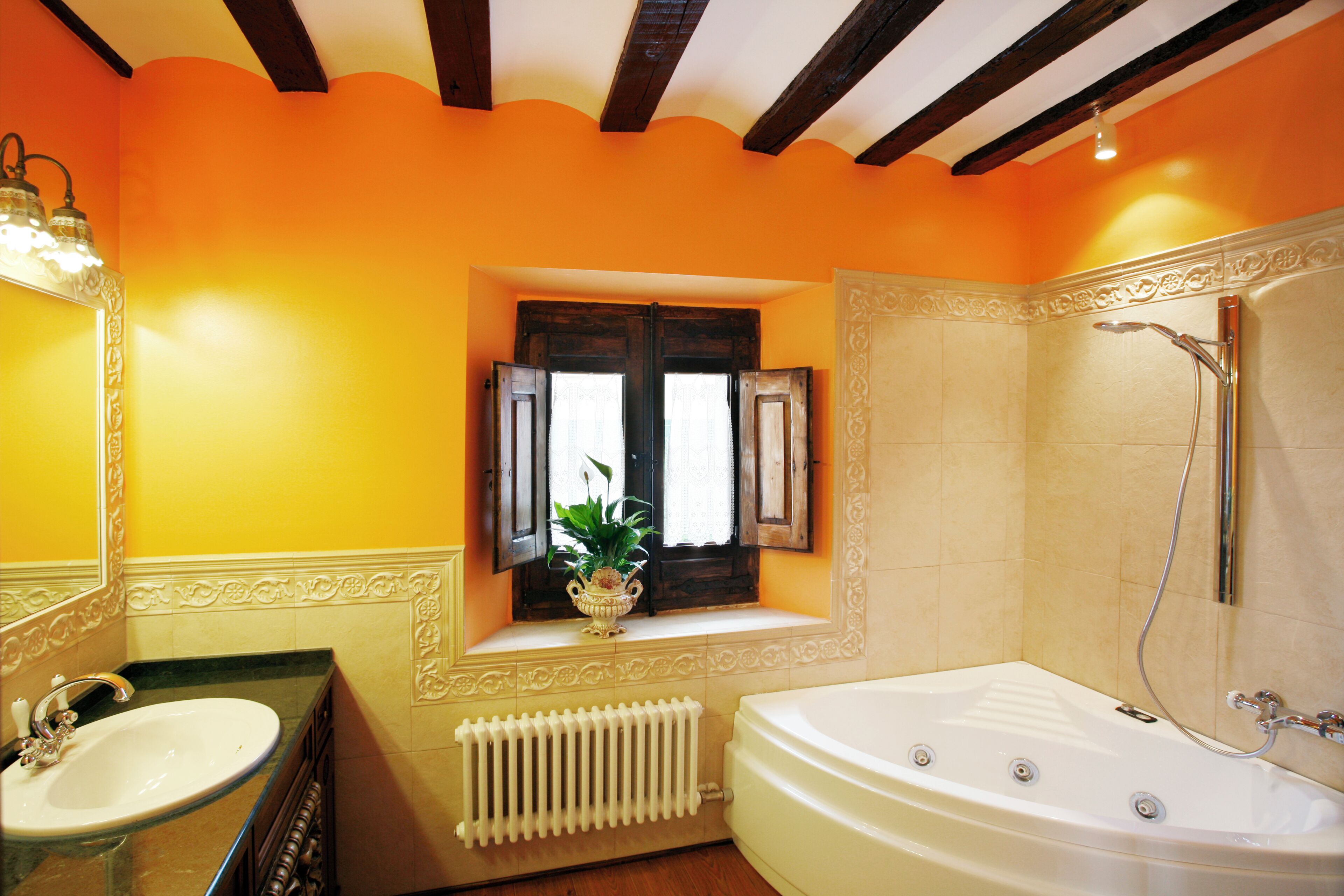 A bathroom with a bathtub, a window with shutters, and a radiator.