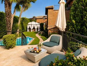 Un patio con mobiliario exterior, piscina y jardín.